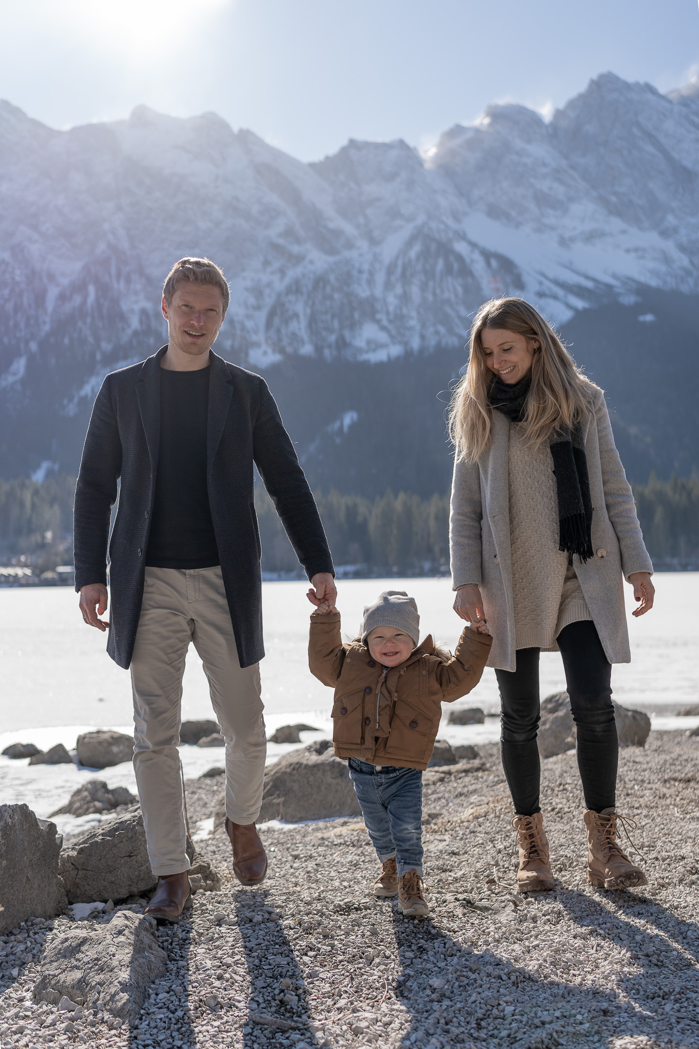 Vater, Mutter und Sohn laufen beim Familienshooting auf die Kamera zu mit dem Eibsee und der Zugspitze im Hintergrund